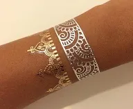 Gold and silver metallic flash tattoo cuff designs on a guest's wrist