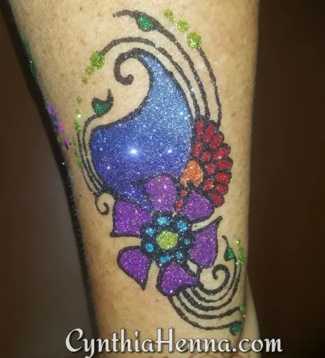 Freehand glitter paisley in blue, purple and red on a leg