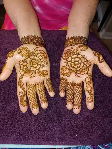 Two palms with matching henna flower medallions and lace-work fingertips