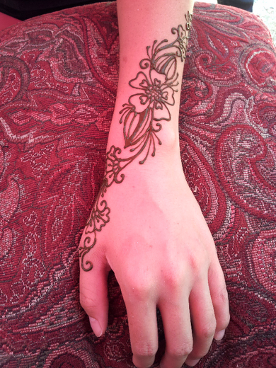 Simple henna flower and vine trailing along the wrist and hand
