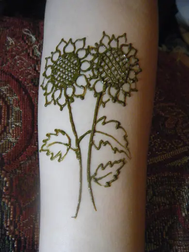 Two henna sunflowers with leaves drawn on a forearm